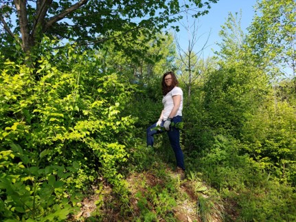 Girl stands near bushes and tree