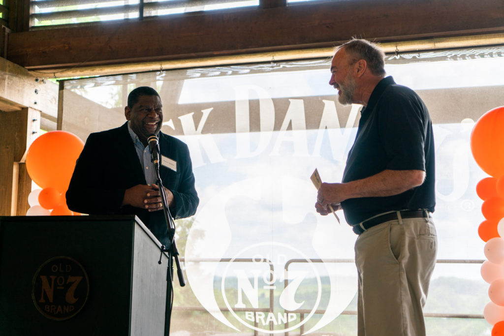 Two men smile in front of a podium