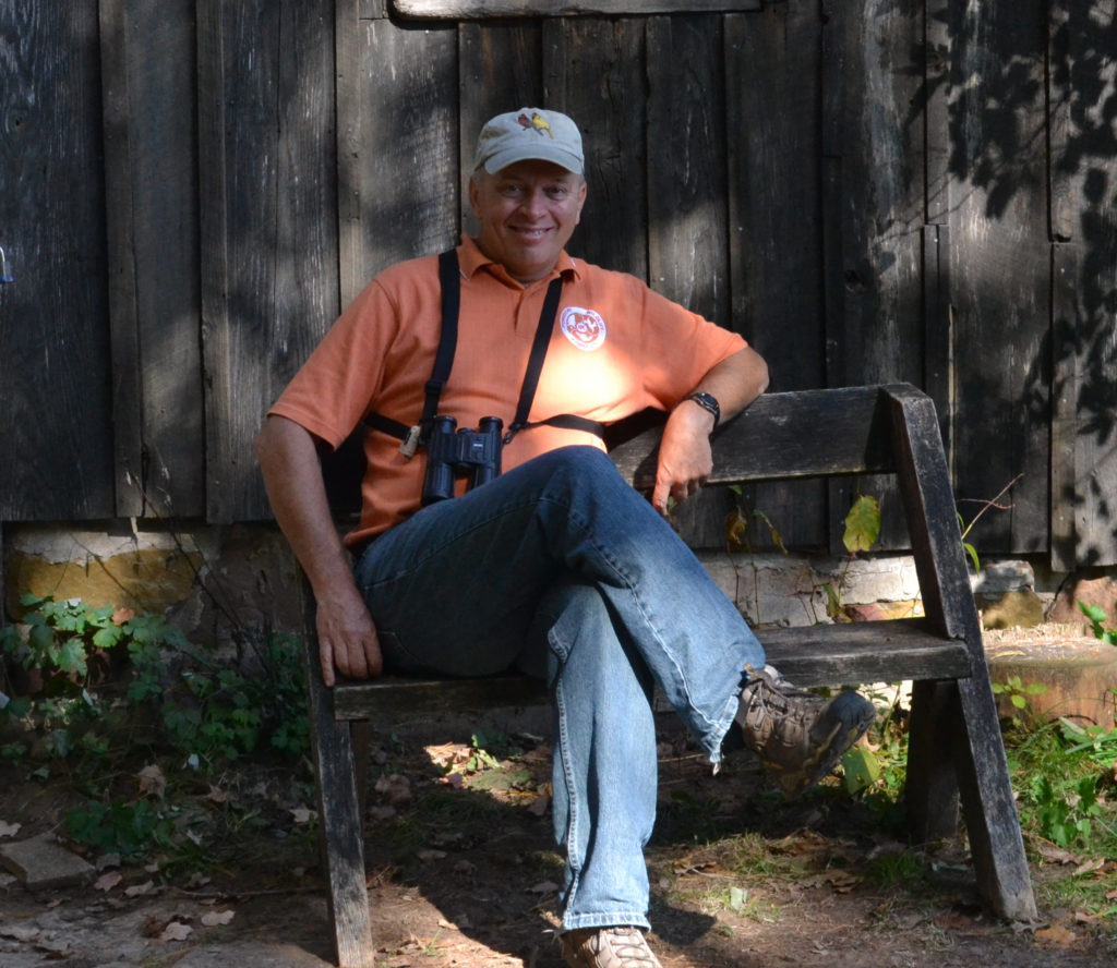 Man sits on bench in front of cabin.