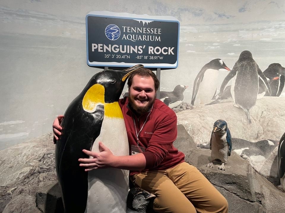 A UT student poses with a penguin statue at the Tennessee Aquarium in Chattanooga.