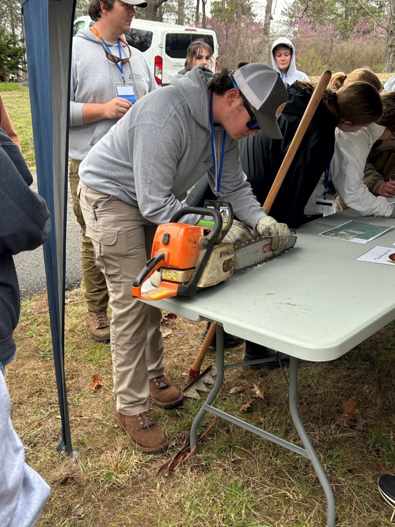 A student participates in chainsaw sharpening during field team competition at The Wildlife Society 2024 Southeastern Student Conclave.