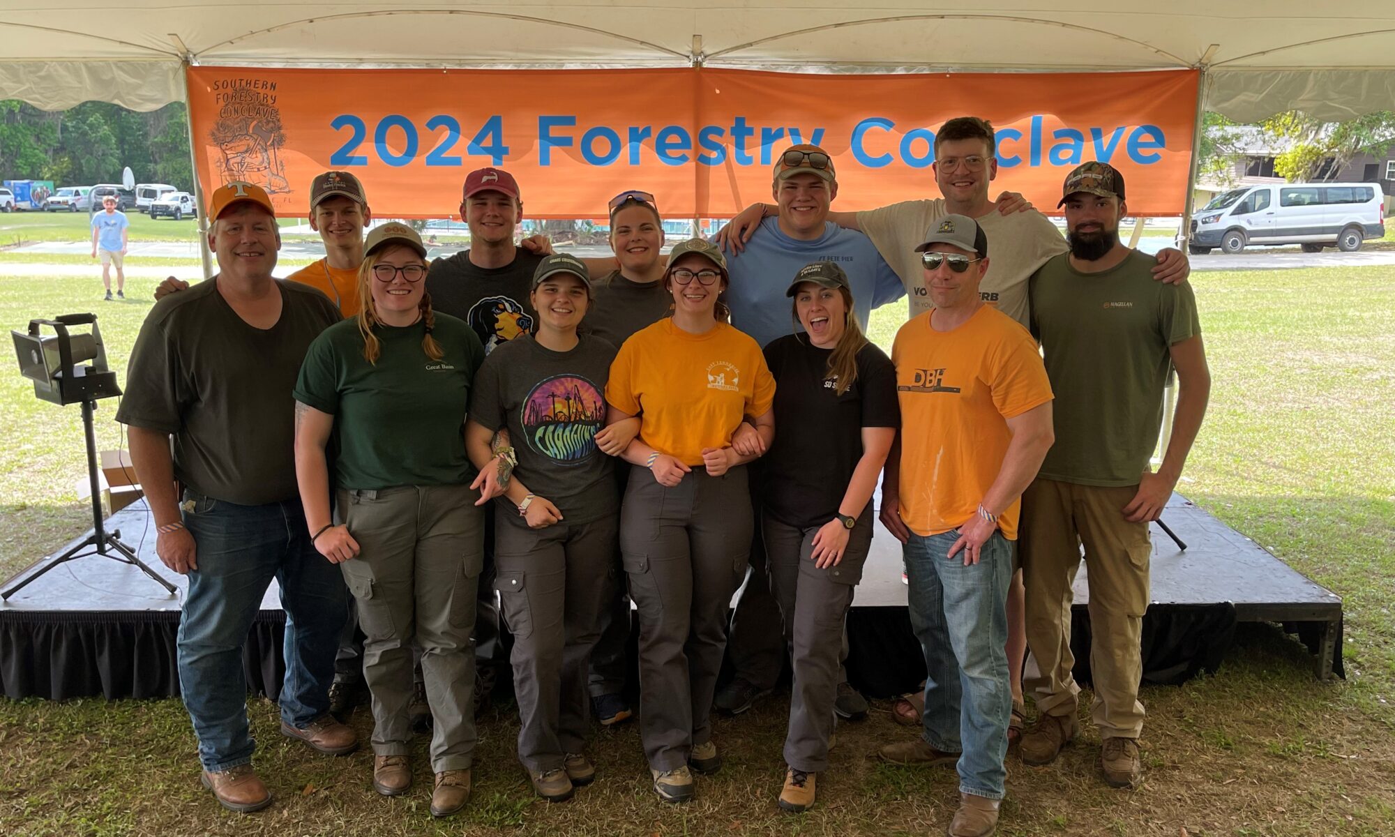 Twelve people post in front of a 2024 Forestry Conclave sign.