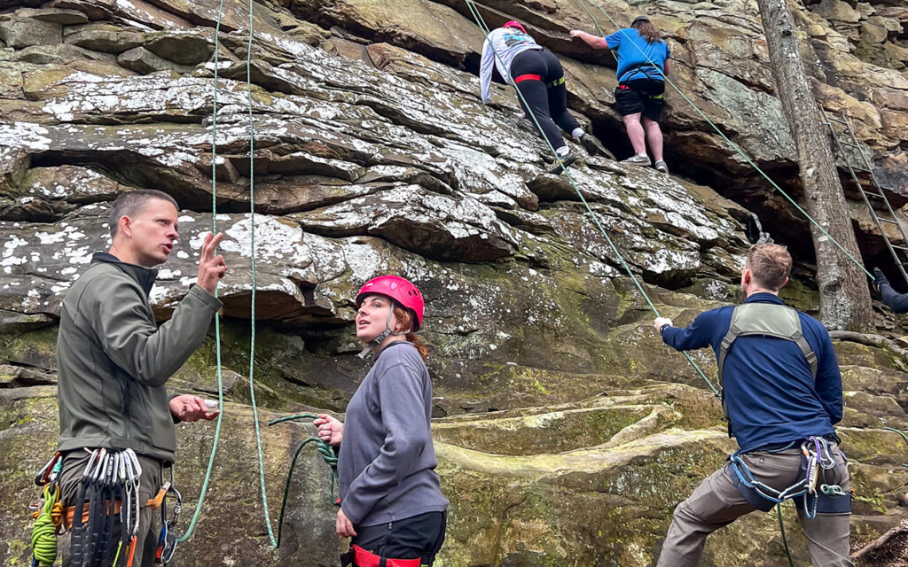 Students climb rock face as part of outdoor recreation and management class.
