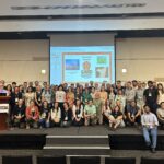 Dozens of people stand and sit on a platform at the second GARD conference at Ghent University in Belgium.