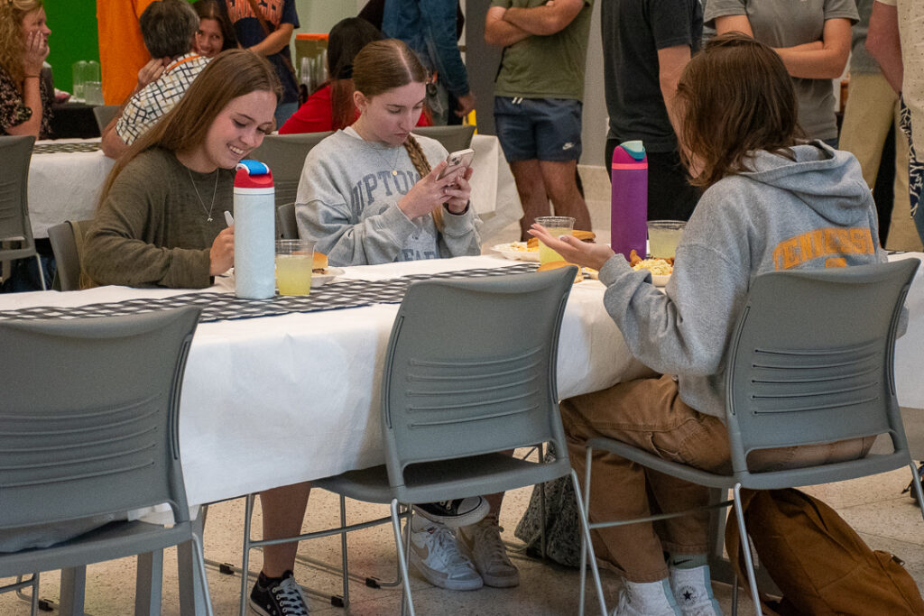 Three women sit at a table eating and talking.