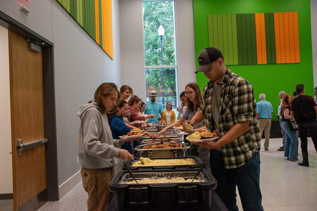 People form two lines around a buffet table to get food.