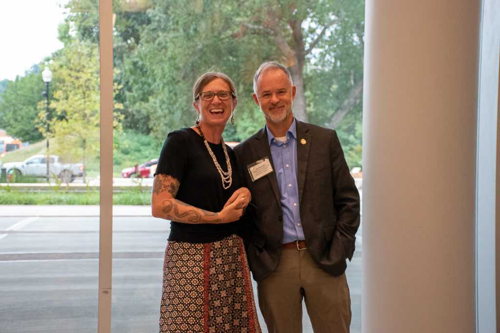 A woman and man stand next to each other smiling.