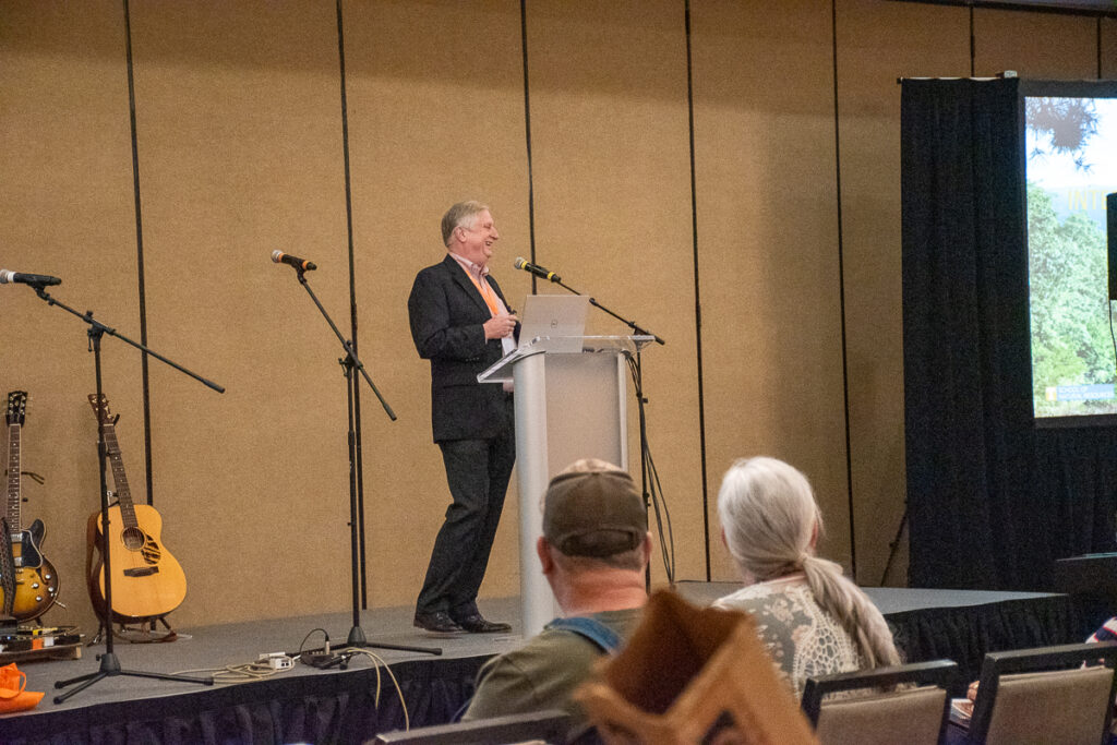 Dr. Don Hodges gives a speech on a stag to a group of people sitting in chairs.