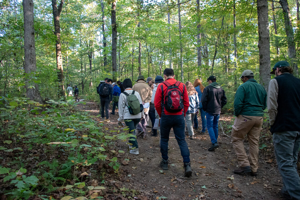 People walk along a trail in a wooded area.