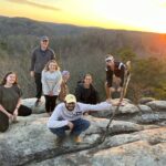 Seven people kneel or stand on boulders in Big South Fork National River and Recreation Area.