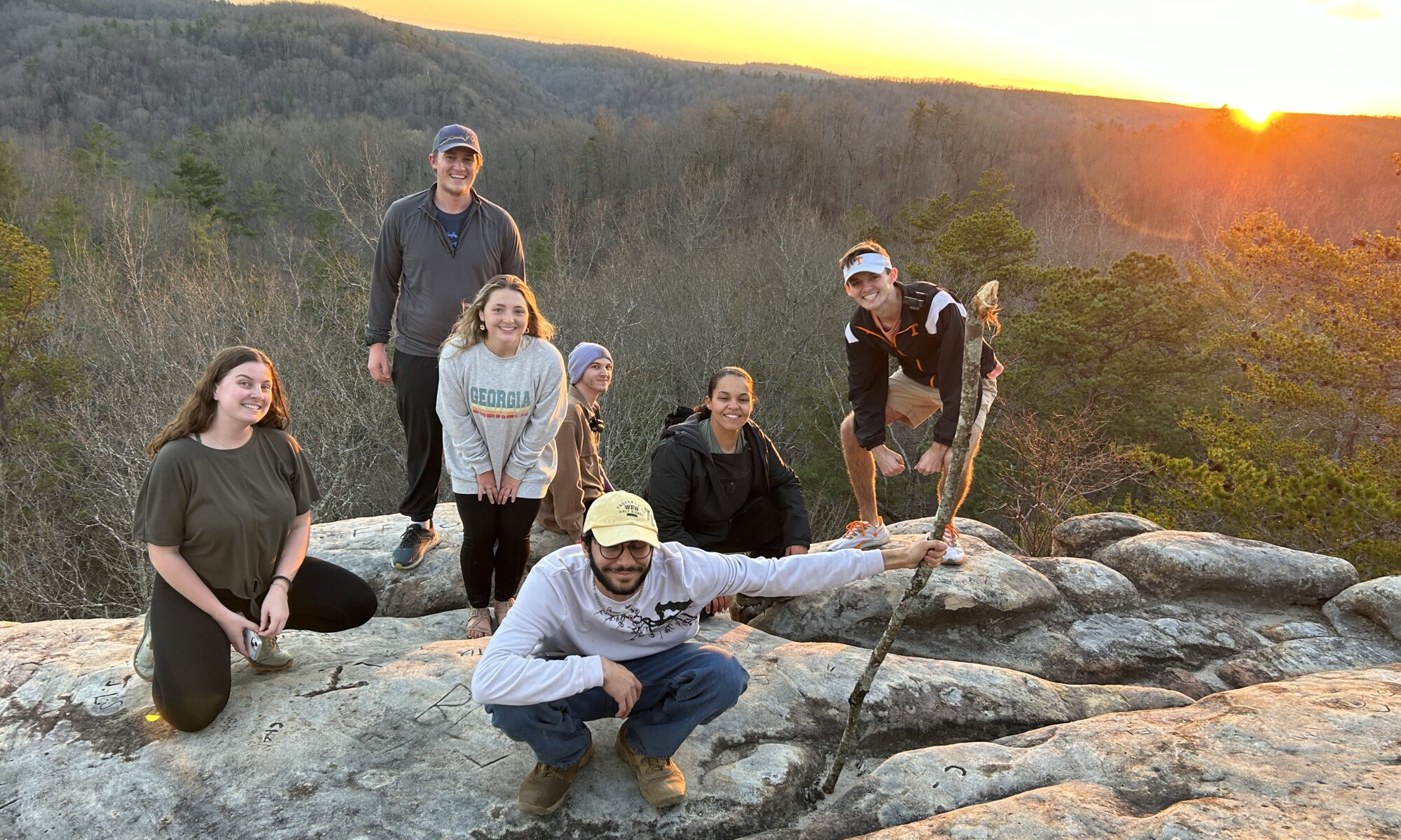Seven people kneel or stand on boulders in Big South Fork National River and Recreation Area.
