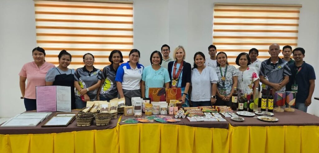 Several people pose behind a table filled with items.