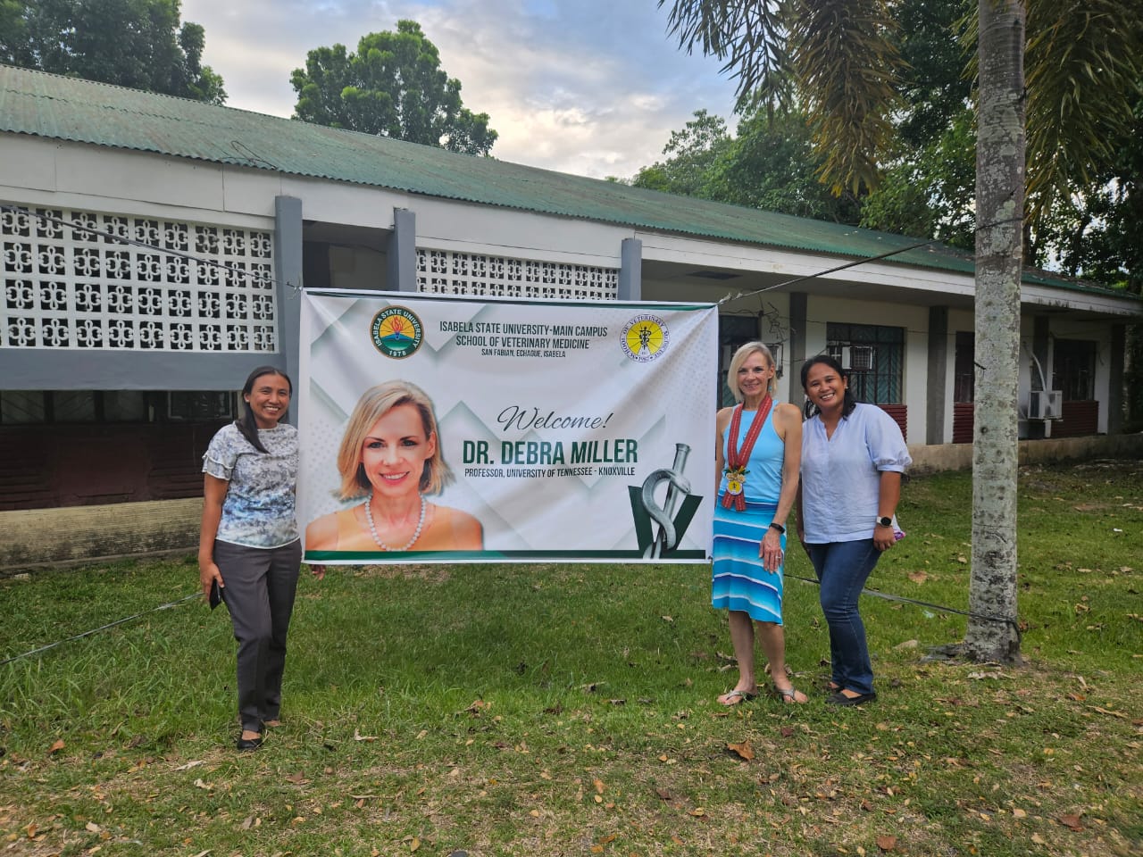 Three people stand next to a sign with a person's face on it.