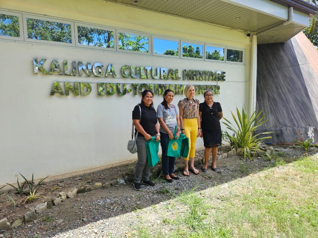 Four people stand in front of a building's sign.