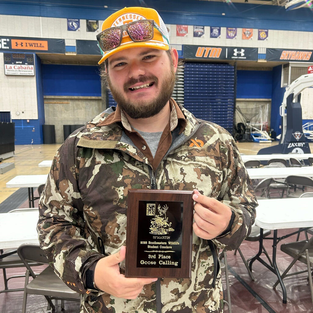 One person wearing an orange cap holds a plaque.