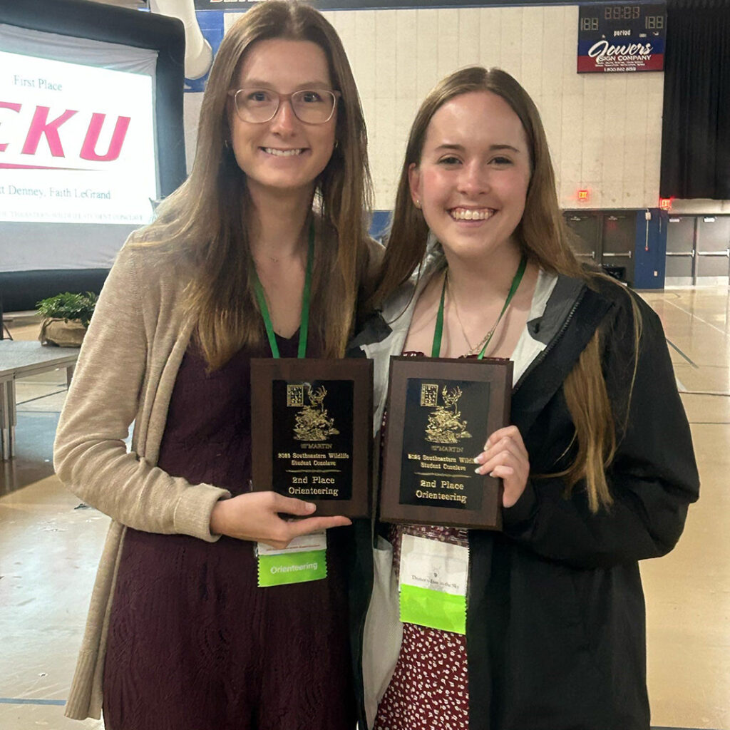 Two people hold plaques.