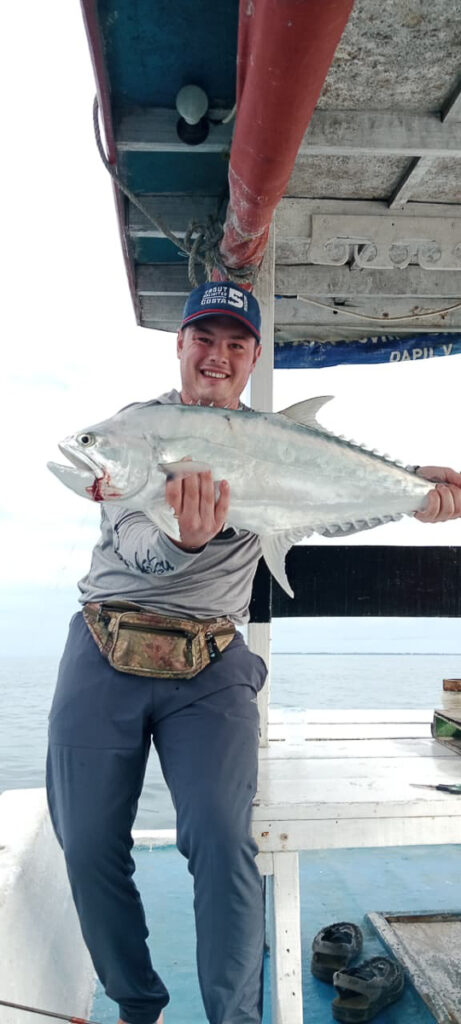 A person holds a fish on a boat.