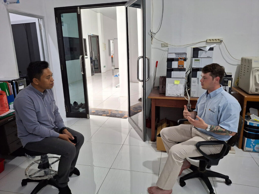 Two people sit and talk inside a room.