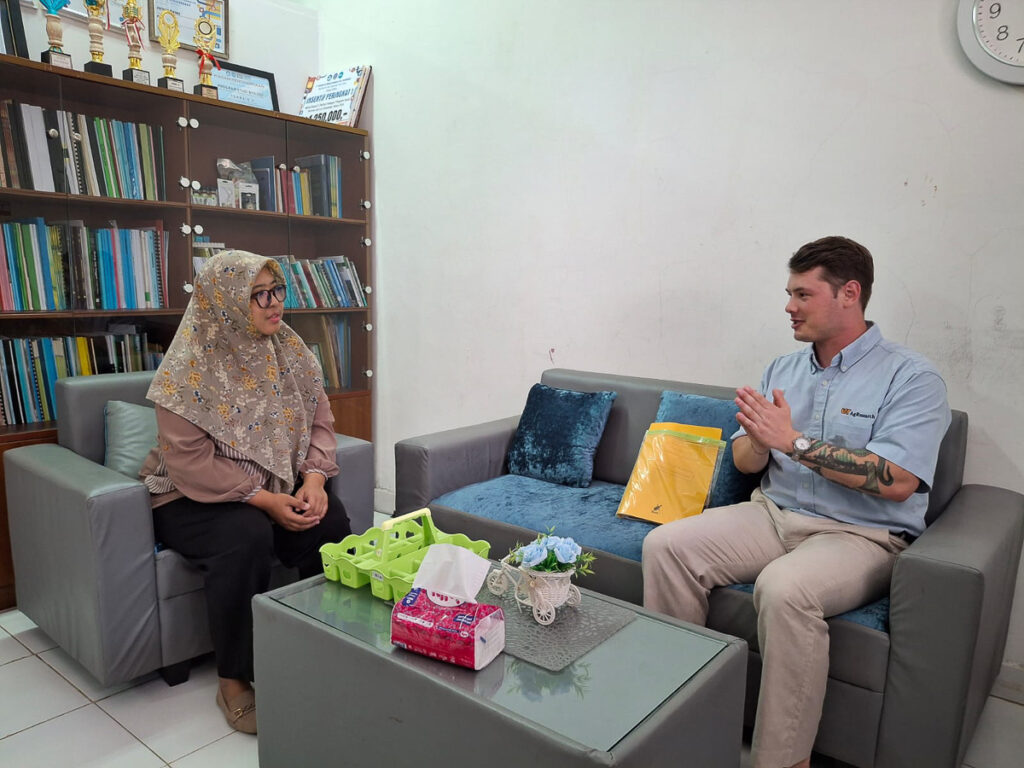 Two people sit on couches and talk in a room.