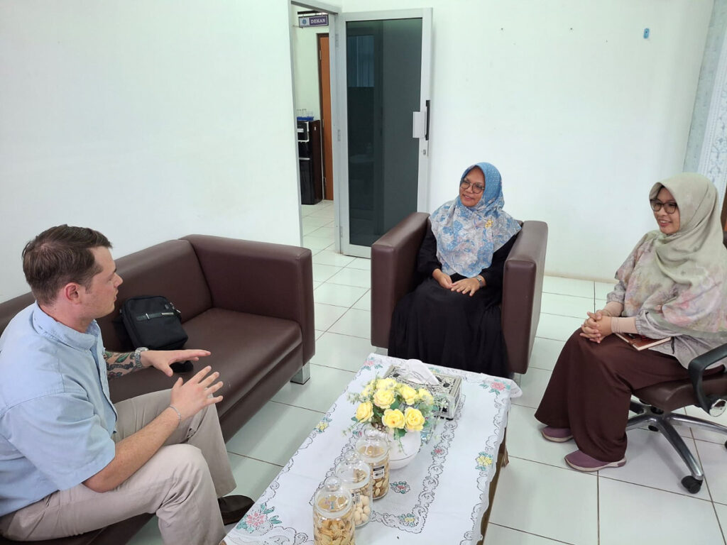 Three people sit and talk in a room.