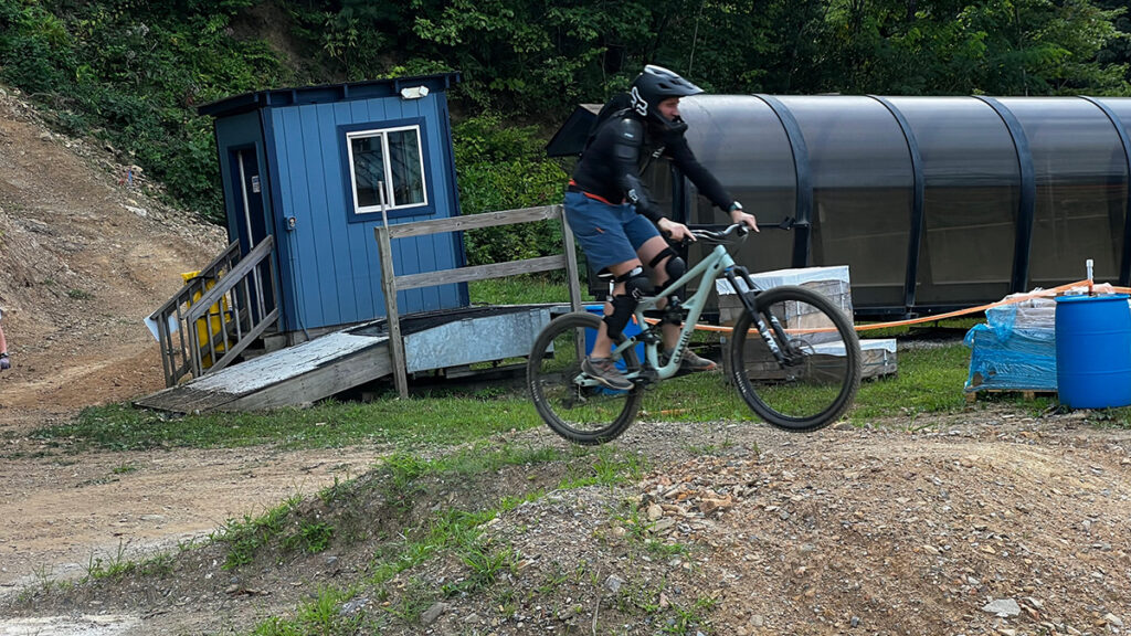 Person rides bike through the air over dirt.