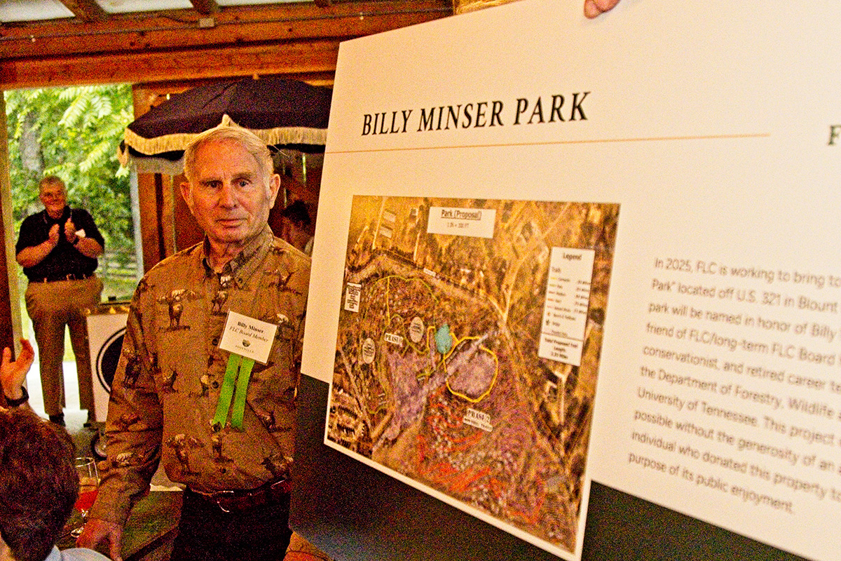 Person wearing name tag stands next to rendering of park named after Billy Minser.