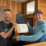 One person shakes another person's hand while holding a certificate.