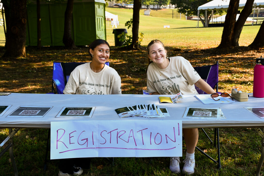 Two people sit behind a registration table.