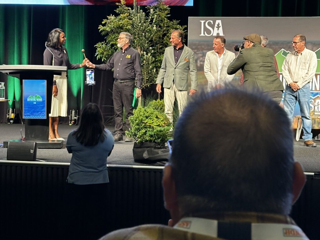 Six people stand on a stage next to a podium.