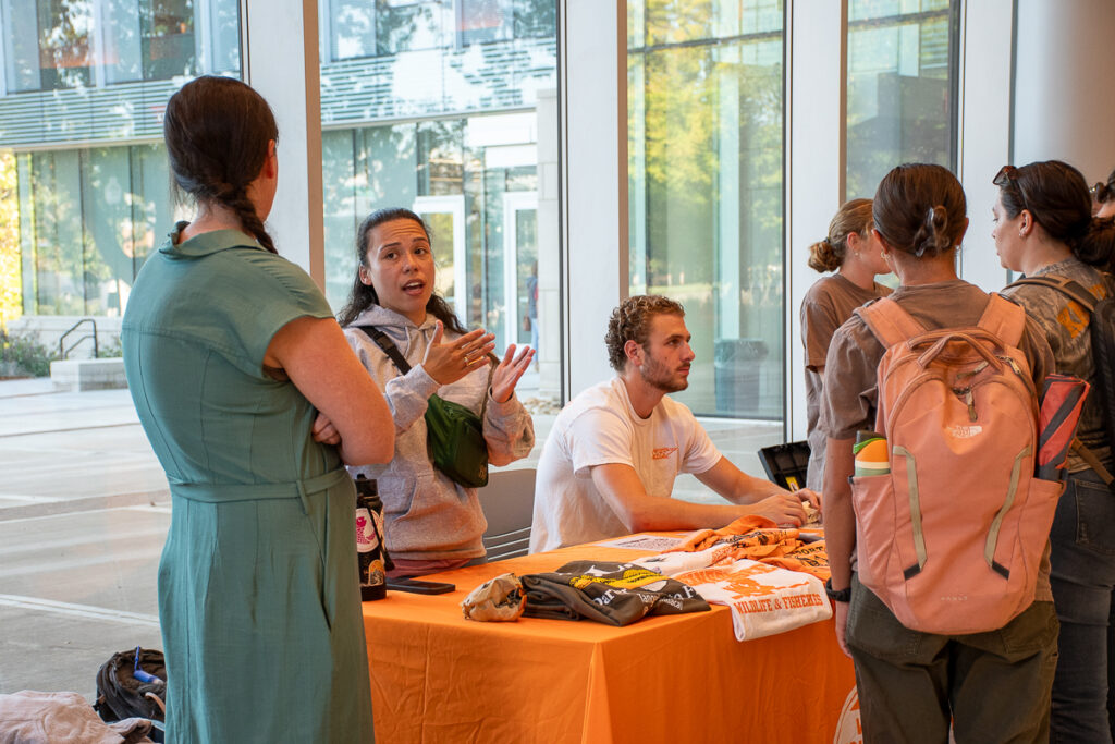 Six people stand or sit and talk around a table in a building on the UT Institute of Agriculture campus.