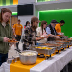 Seven people line up at a buffet table in a building on the UT Institute of Agriculture campus.