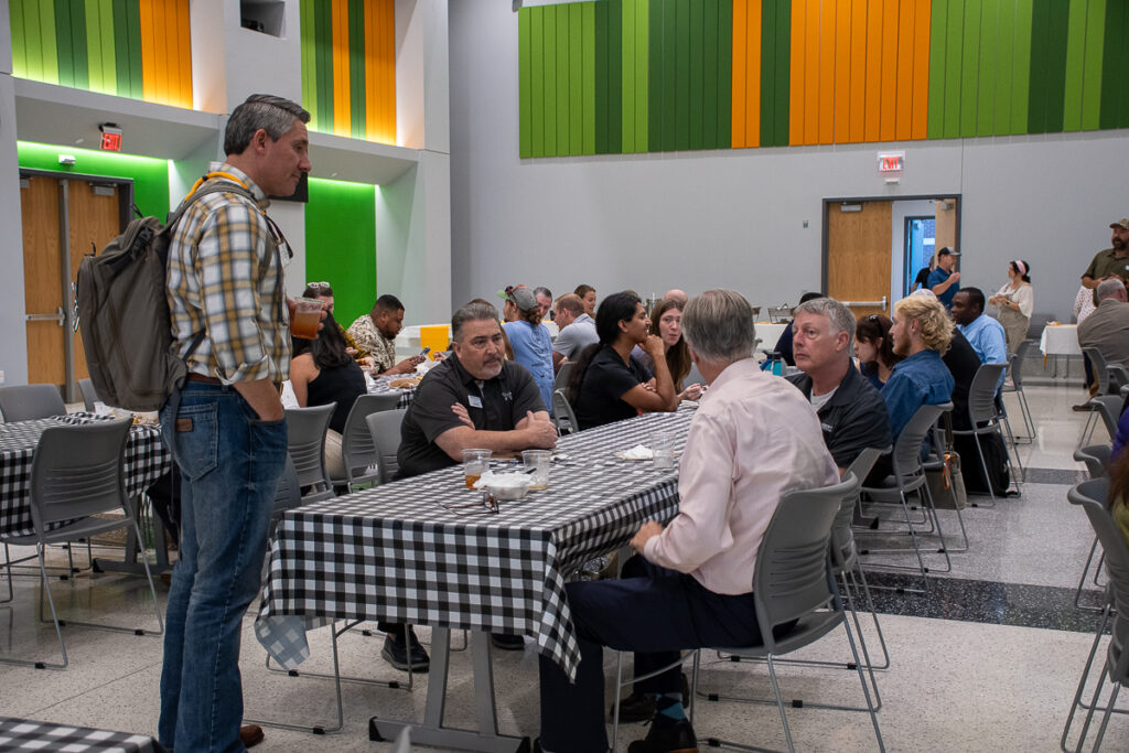 One person stands while three others sit at a table talking in a building on the UT Institute of Agriculture campus.