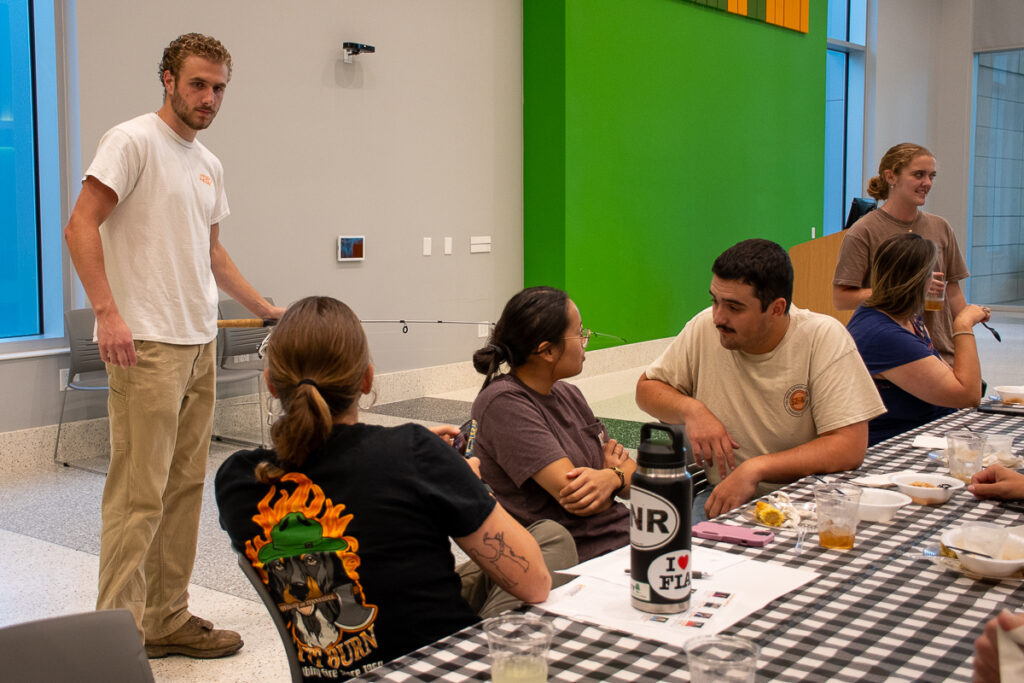 Six people sit or stand around a table in a building on the UT Institute of Agriculture campus.