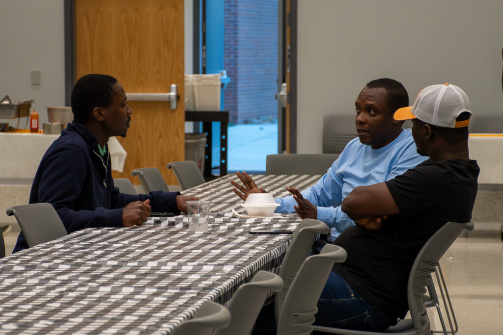 Three people sit at a table and talk in a building on the UT Institute of Agriculture campus.