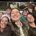 Fourteen people pose together at the Society of American Foresters annual convention while two other people look beyond them.