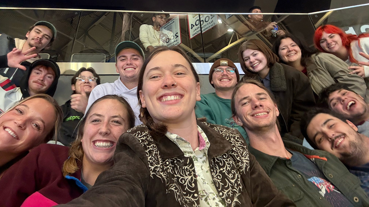Fourteen people pose together at the Society of American Foresters annual convention while two other people look beyond them.