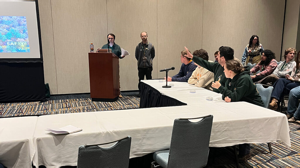 Twelve people sit or stand in a room for the Society of American Foresters annual quiz bowl.