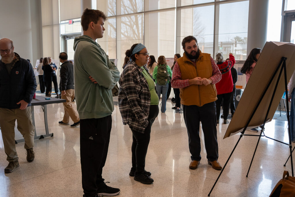 Three people talk in front of a poster while others look at other posters in the Agriculture and Natural Resources Building at the UT Institute of Agriculture.