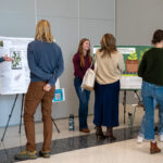 Six people talk in front of three posters in the Agriculture and Natural Resources Building at the UT Institute of Agriculture.