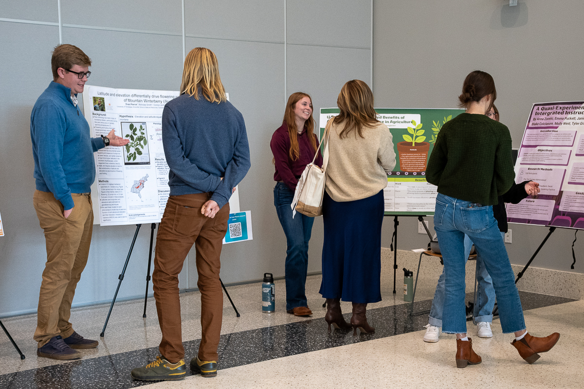 Six people talk in front of three posters in the Agriculture and Natural Resources Building at the UT Institute of Agriculture.