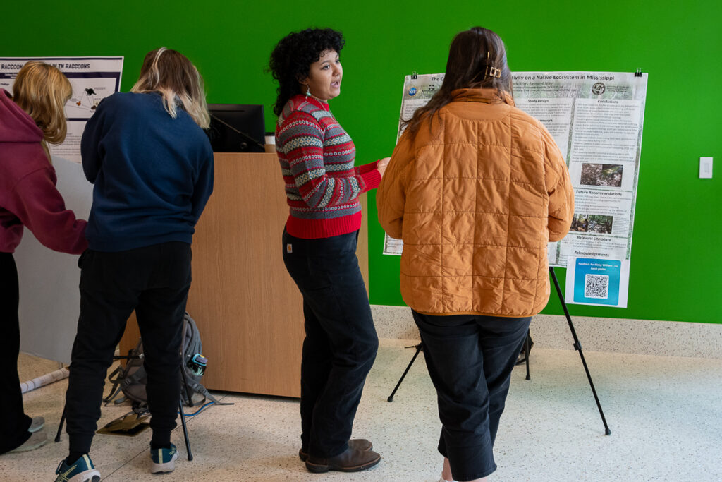 Four people talk in front of a poster in the Agriculture and Natural Resources Building at the UT Institute of Agriculture.