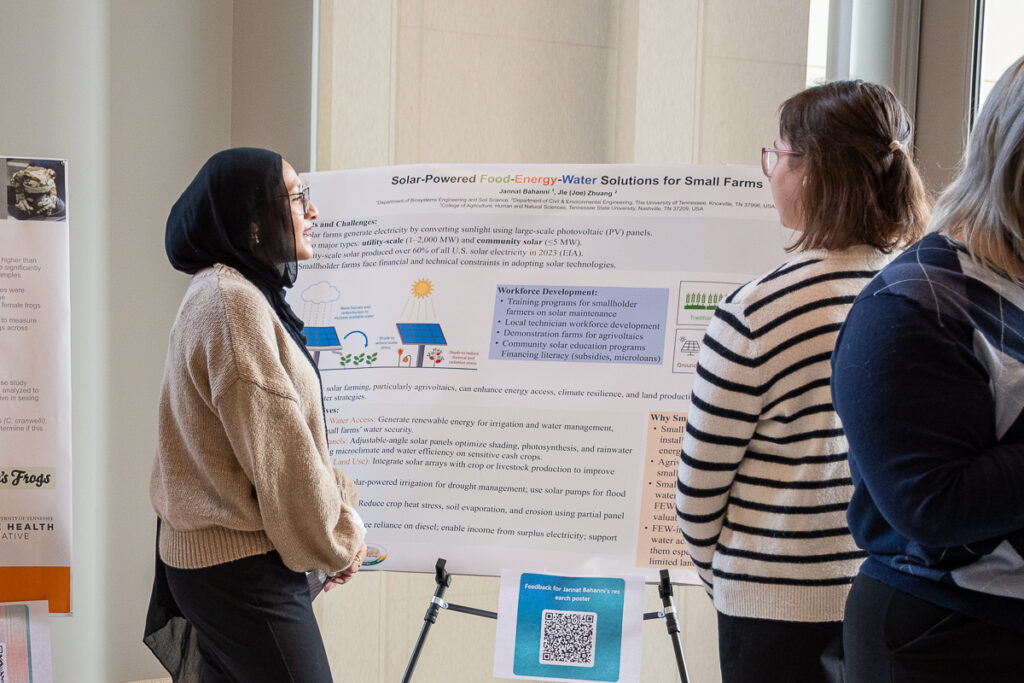 Two people talk in front of a poster in the Agriculture and Natural Resources Building at the UT Institute of Agriculture.