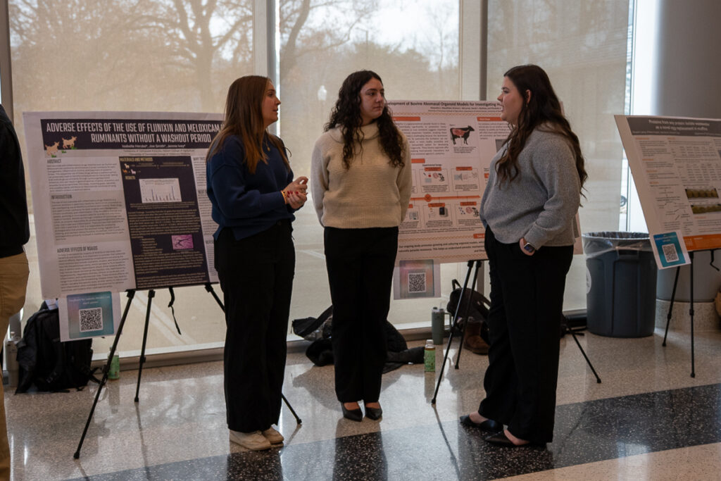Three people stand in front of posters in the Agriculture and Natural Resources Building at the UT Institute of Agriculture.
