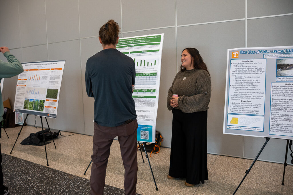 Two people stand by a poster in the Agriculture and Natural Resources Building at the UT Institute of Agriculture.