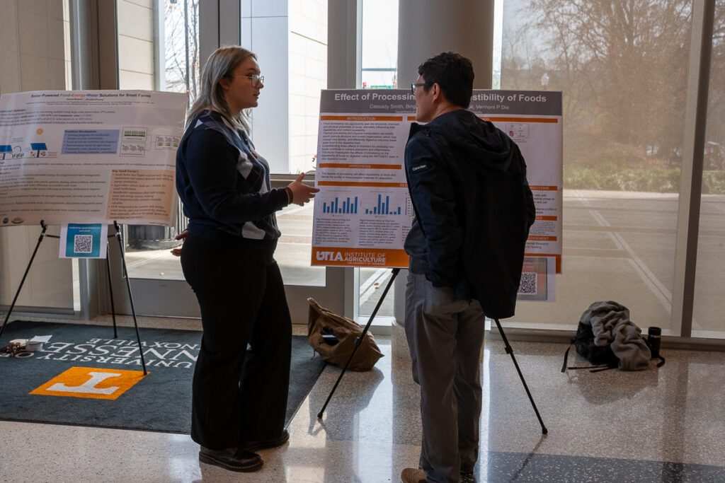 Two people talk in front of a poster in the Agriculture and Natural Resources Building at the UT Institute of Agriculture.