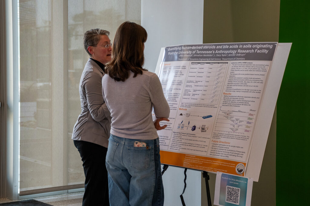 Two people talk in front of a poster in the Agriculture and Natural Resources Building at the UT Institute of Agriculture.