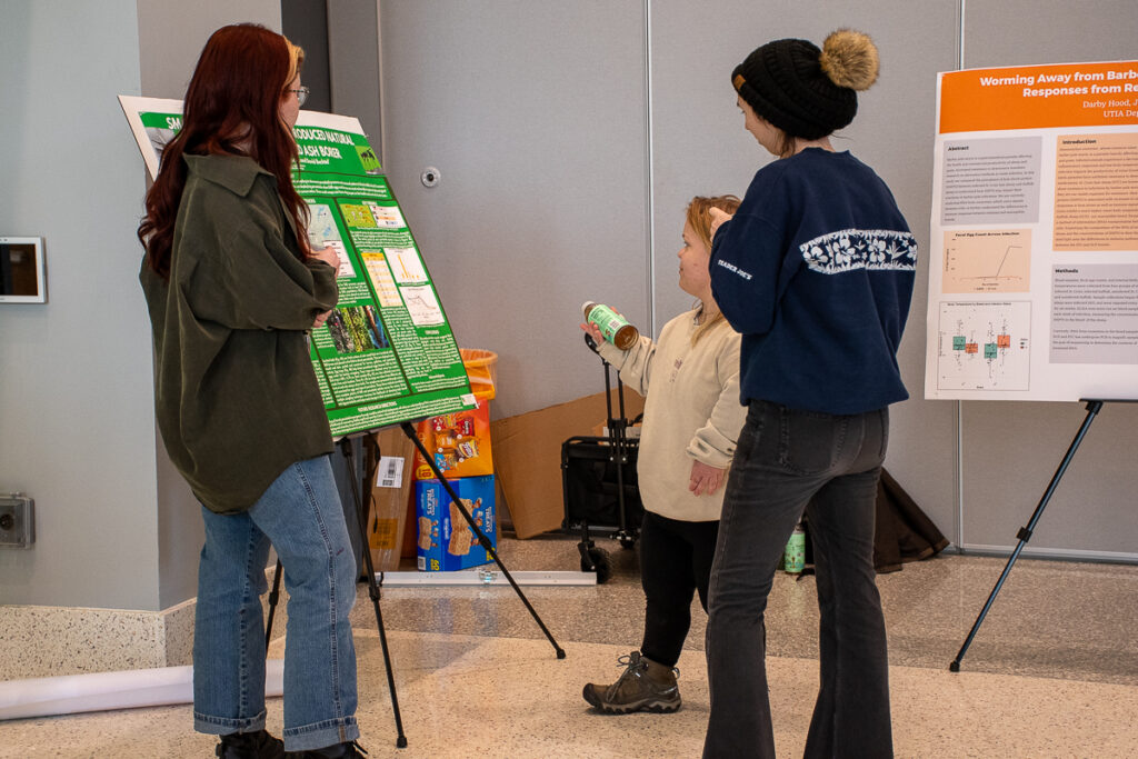 Three people talk in front of a poster in the Agriculture and Natural Resources Building at the UT Institute of Agriculture.