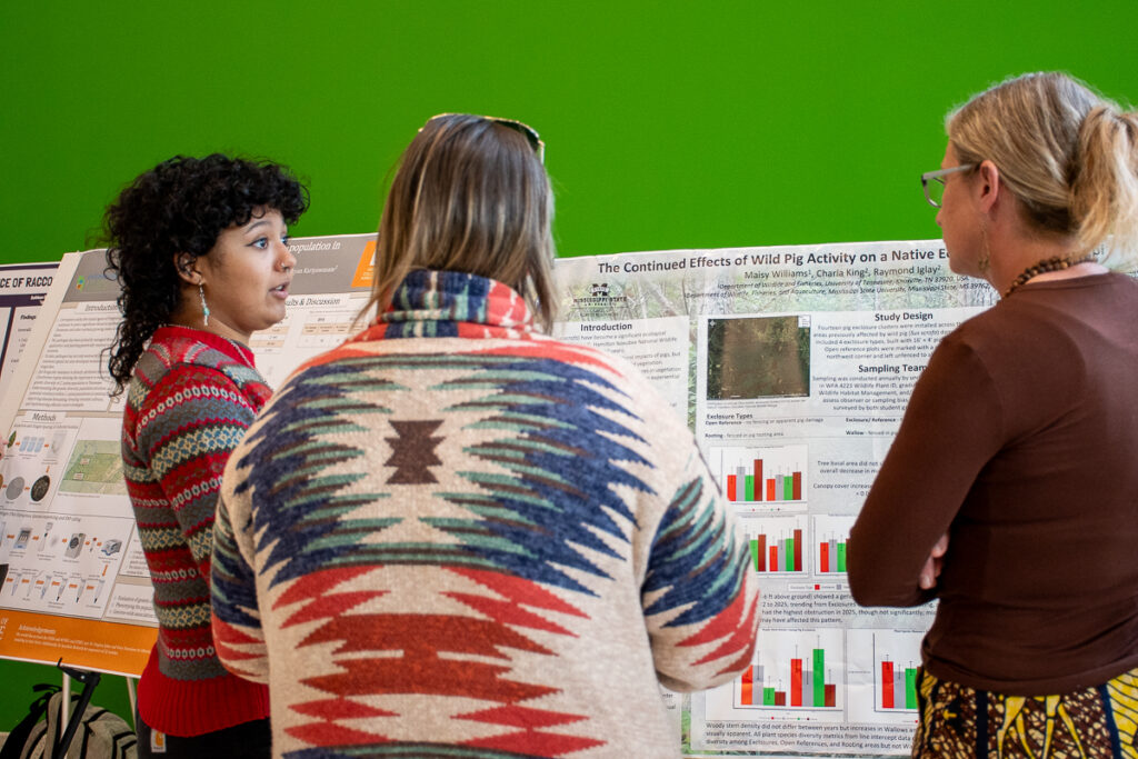 Three people talk in front of a poster in the Agriculture and Natural Resources Building at the UT Institute of Agriculture.
