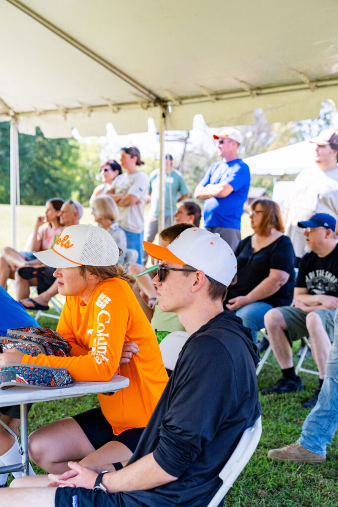 People sitting under a tent listen to a presentation at the Outdoor Enthusiast Expo.