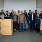 Fifteen people stand in a room by a podium on the UT Institute of Agriculture campus.